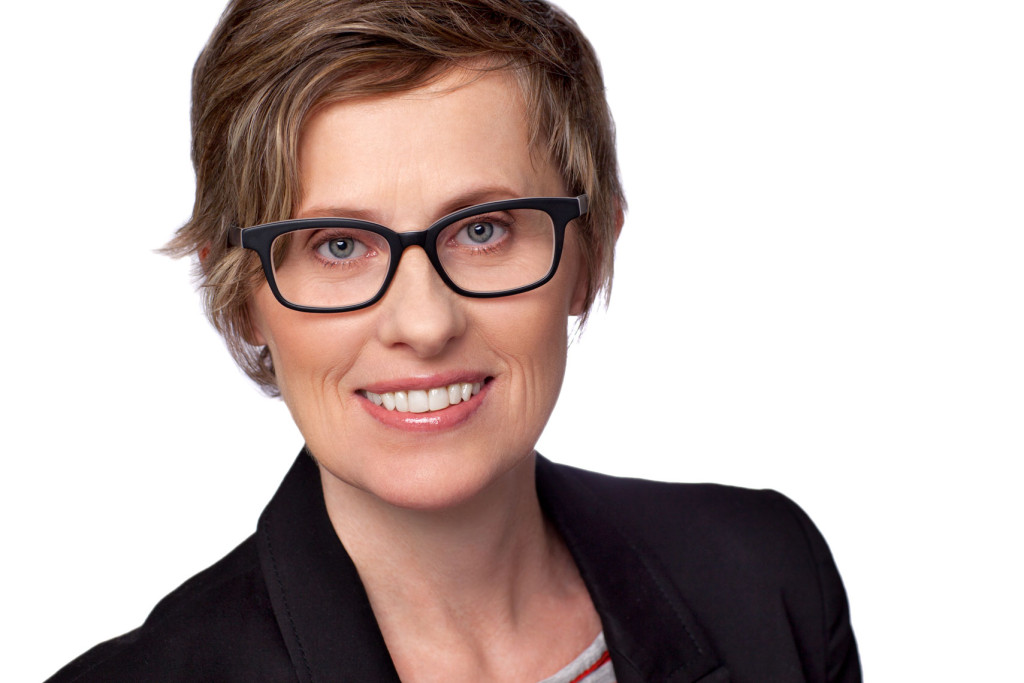 retouching Headshot of woman with black glasses, short blonde hair, blue eyes. Photographed on white background.