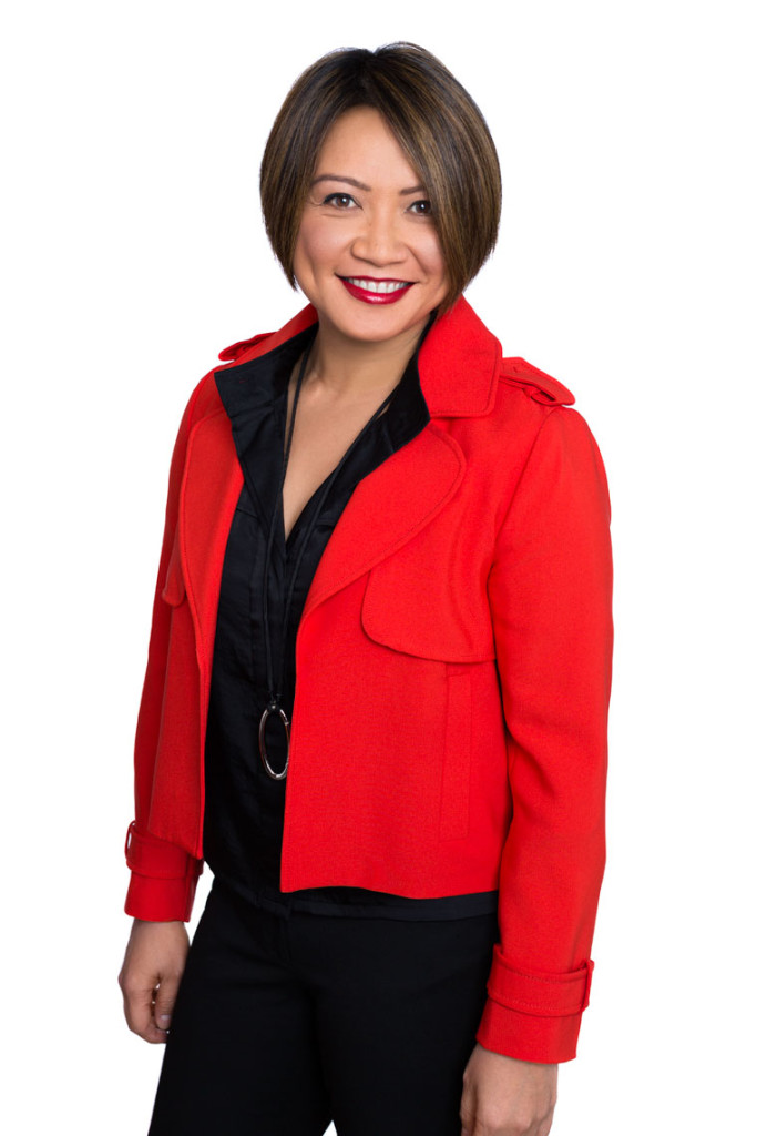 Woman in red jacket in 3/4 body company headshot.