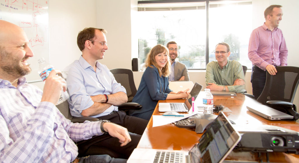 Tech company employees share a laugh in a meeting