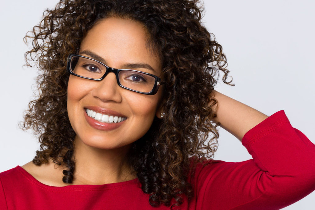 Headshot of smiling woman with curly hair and glasses