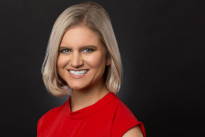 Smiling blonde woman in red blouse. Perfect headshot wardrobe.